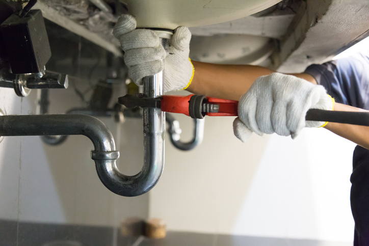 Plumber fixing sink pipe with adjustable wrench