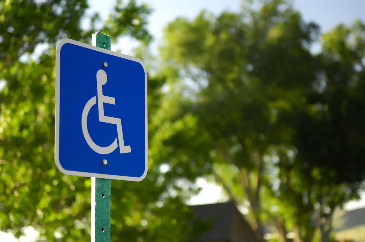 An International Symbol of Access sign in front of two trees