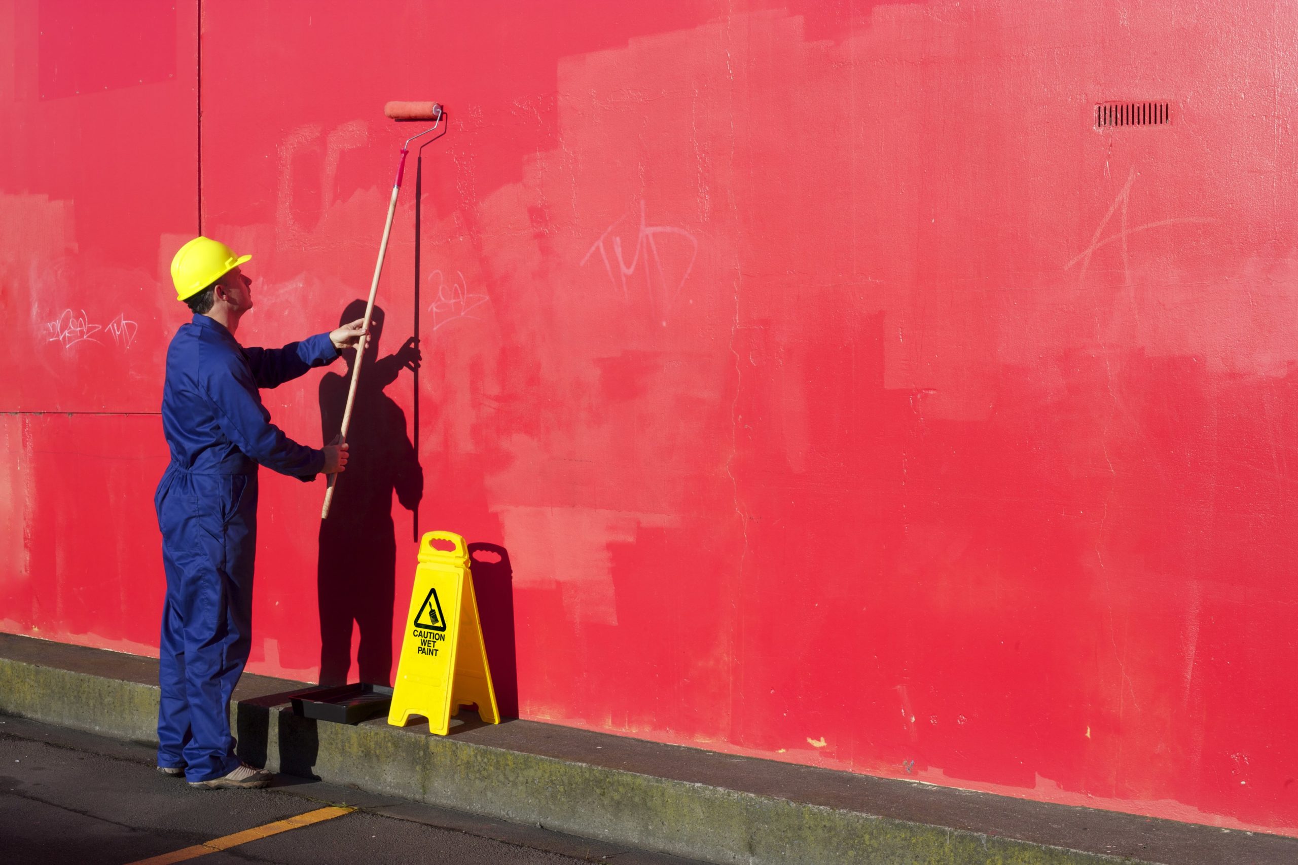 A contractor painting a Los Angeles building's wall red