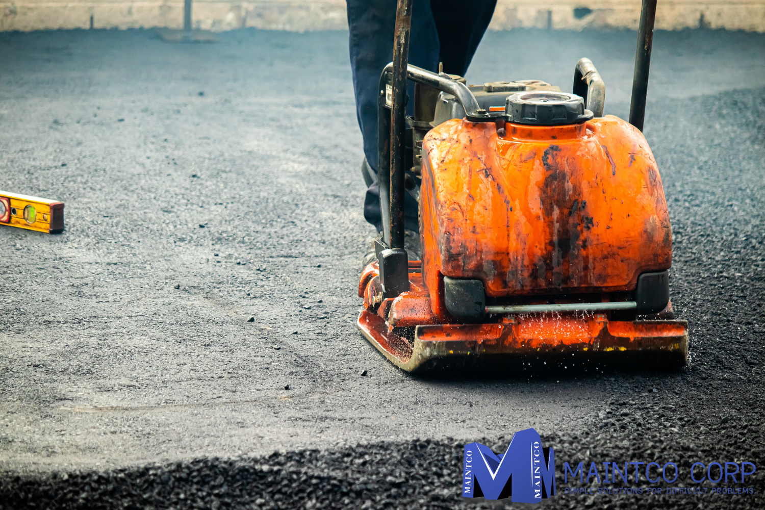 Maintco employee smoothening a parking lot's new asphalt