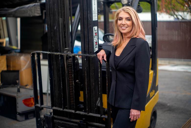 Maintco Corporation's CEO, Inna Tuler, smiling while standing next to a forklift