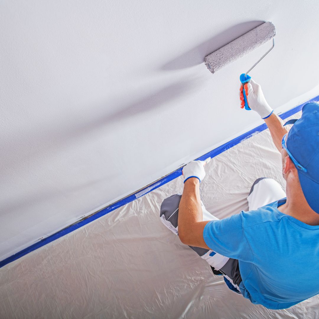 Image of a commercial painting facility, featuring professional painters working on a project, applying paint to walls and surfaces with precision and expertise.