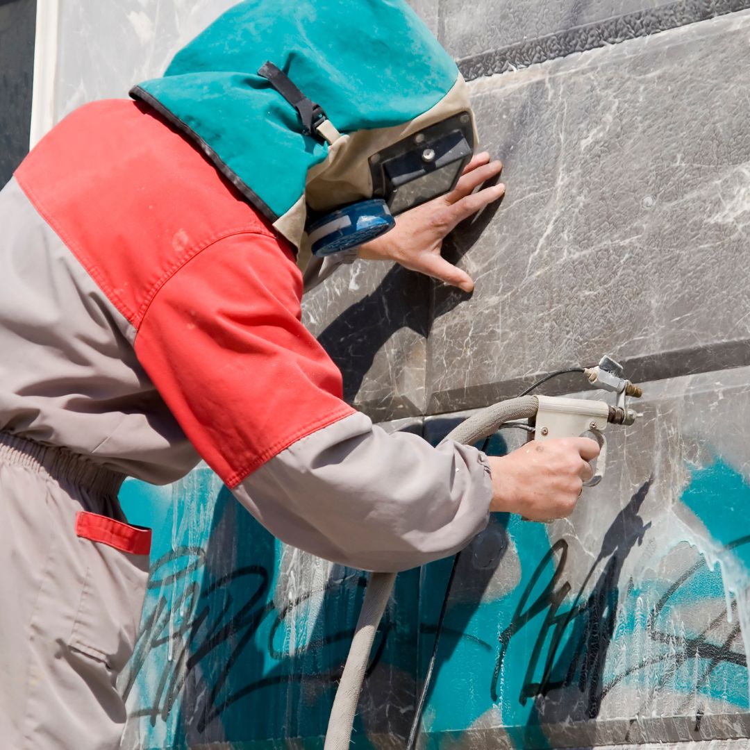 Image illustrating commercial graffiti removal in progress, with a team of professionals using specialized equipment and techniques to remove graffiti from a commercial building, restoring its clean and pristine appearance.